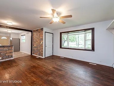 unfurnished living room with dark hardwood / wood-style flooring and ceiling fan