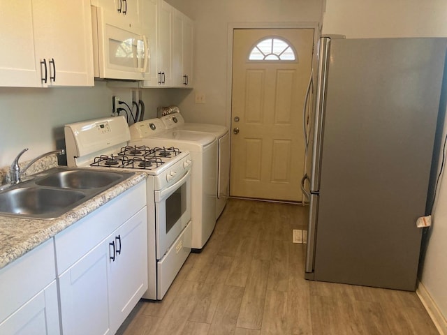 kitchen with white cabinetry, sink, separate washer and dryer, white appliances, and light wood-type flooring