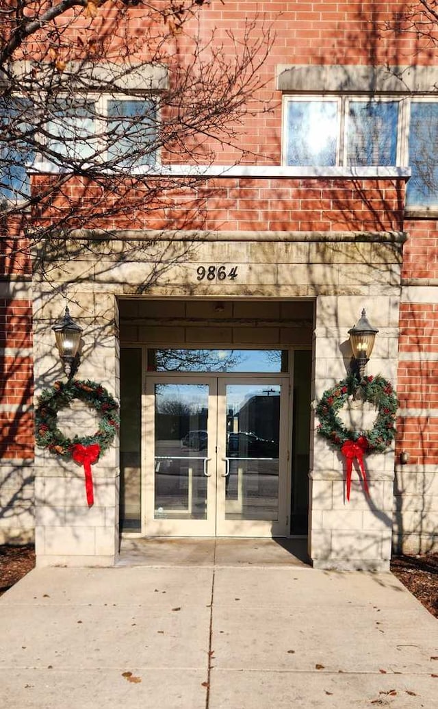 property entrance featuring french doors and brick siding