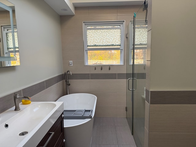 bathroom featuring tile patterned floors, vanity, tile walls, and independent shower and bath