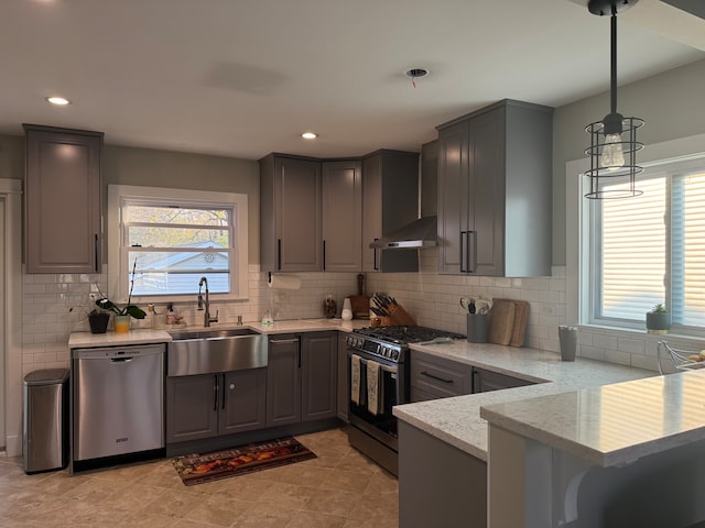 kitchen featuring kitchen peninsula, stainless steel appliances, exhaust hood, sink, and decorative light fixtures