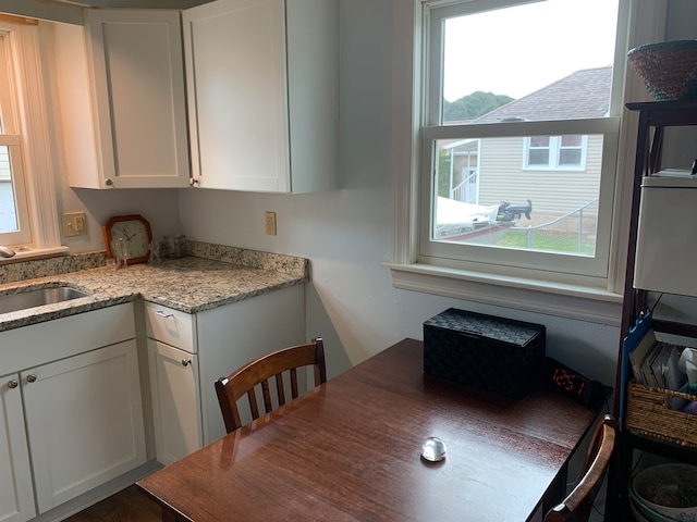 kitchen with white cabinets, light stone counters, and plenty of natural light