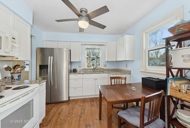 kitchen with sink, white appliances, light hardwood / wood-style flooring, light stone counters, and white cabinets