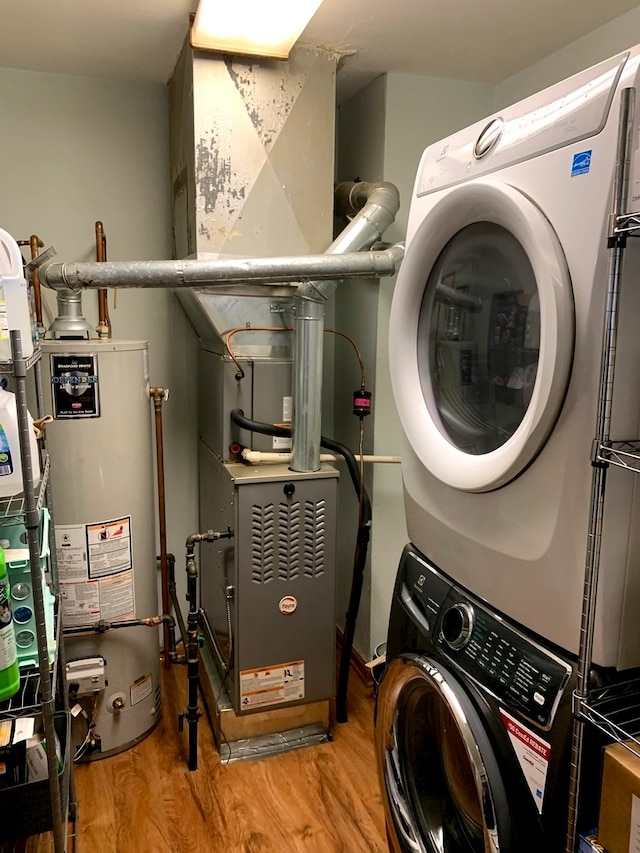 laundry room with water heater, light hardwood / wood-style flooring, and stacked washer and clothes dryer