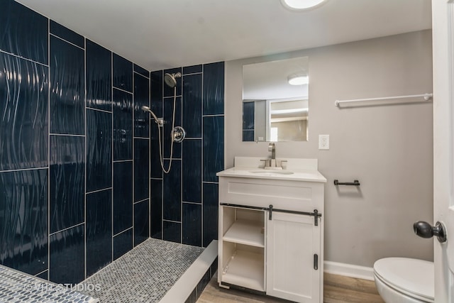 bathroom with vanity, toilet, wood-type flooring, and tiled shower