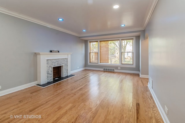 unfurnished living room featuring a stone fireplace, crown molding, and light hardwood / wood-style floors