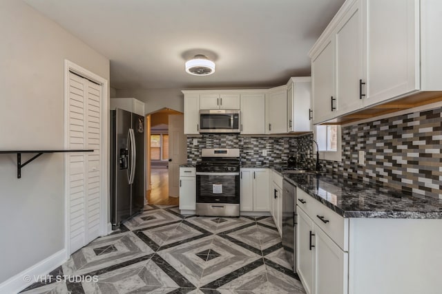 kitchen with dark stone countertops, white cabinetry, appliances with stainless steel finishes, and tasteful backsplash