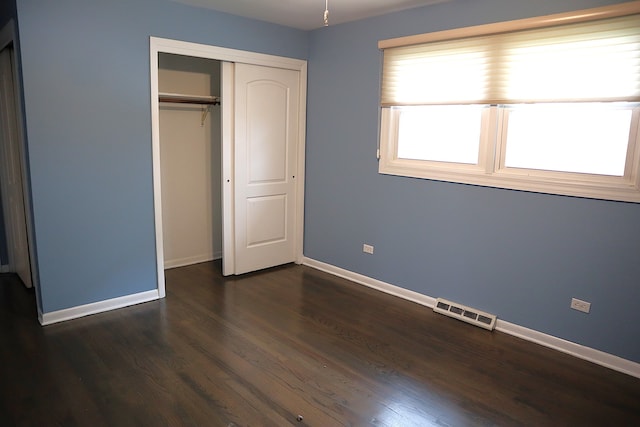 unfurnished bedroom with dark hardwood / wood-style flooring and a closet