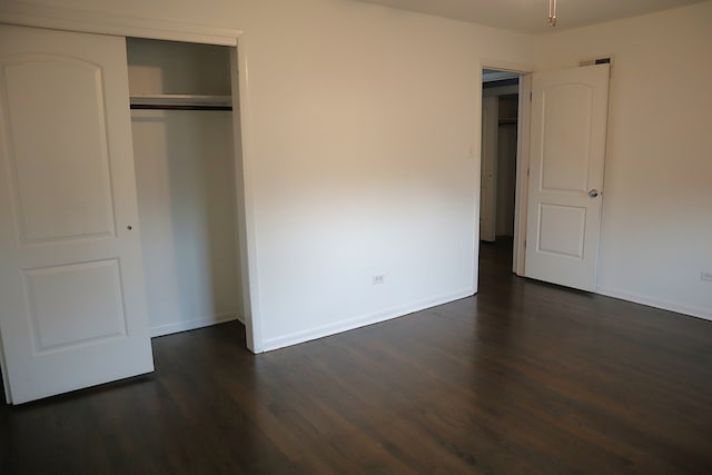 unfurnished bedroom featuring dark hardwood / wood-style flooring and a closet