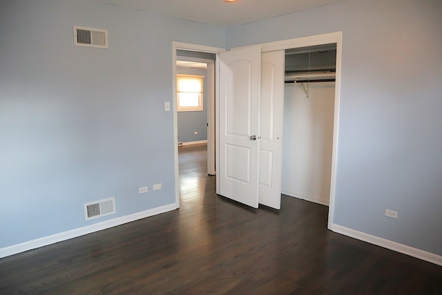 unfurnished bedroom with dark hardwood / wood-style flooring and a closet