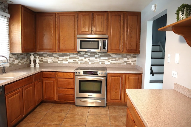 kitchen with tasteful backsplash, sink, light tile patterned floors, and appliances with stainless steel finishes