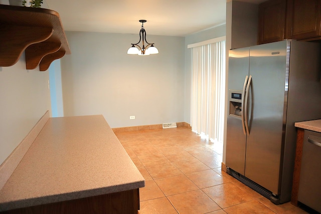 kitchen with a chandelier, pendant lighting, stainless steel appliances, and light tile patterned flooring