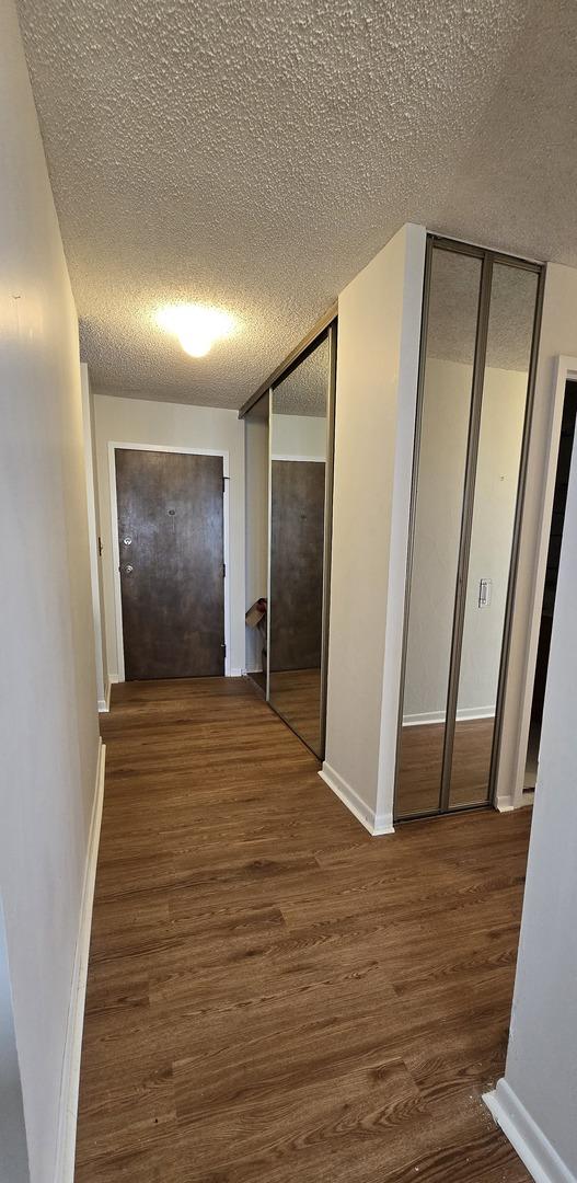 corridor with a wall of windows, dark wood-type flooring, and a textured ceiling