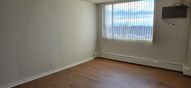 spare room with a wall unit AC, baseboard heating, and hardwood / wood-style floors