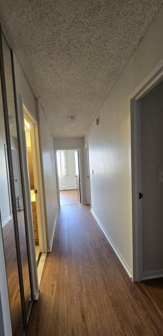 hall with a textured ceiling and wood-type flooring