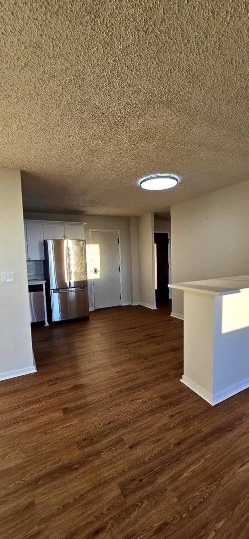 interior space with a textured ceiling, dark wood-type flooring, and baseboards