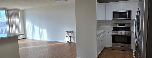 kitchen featuring decorative backsplash, hardwood / wood-style flooring, a textured ceiling, stainless steel appliances, and white cabinets