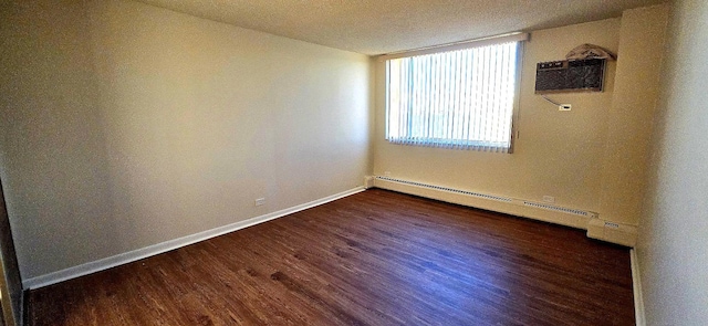 spare room featuring dark wood-style flooring, baseboard heating, a wall mounted AC, and baseboards