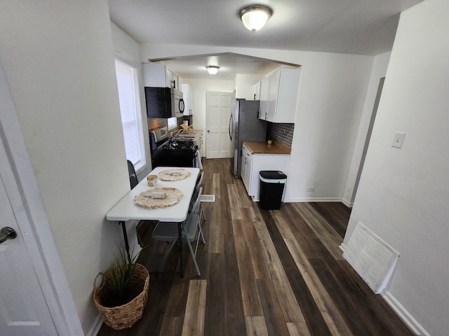 kitchen featuring white cabinets, decorative backsplash, dark hardwood / wood-style flooring, and appliances with stainless steel finishes