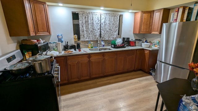 kitchen featuring stainless steel fridge, black range with electric cooktop, light hardwood / wood-style floors, and sink