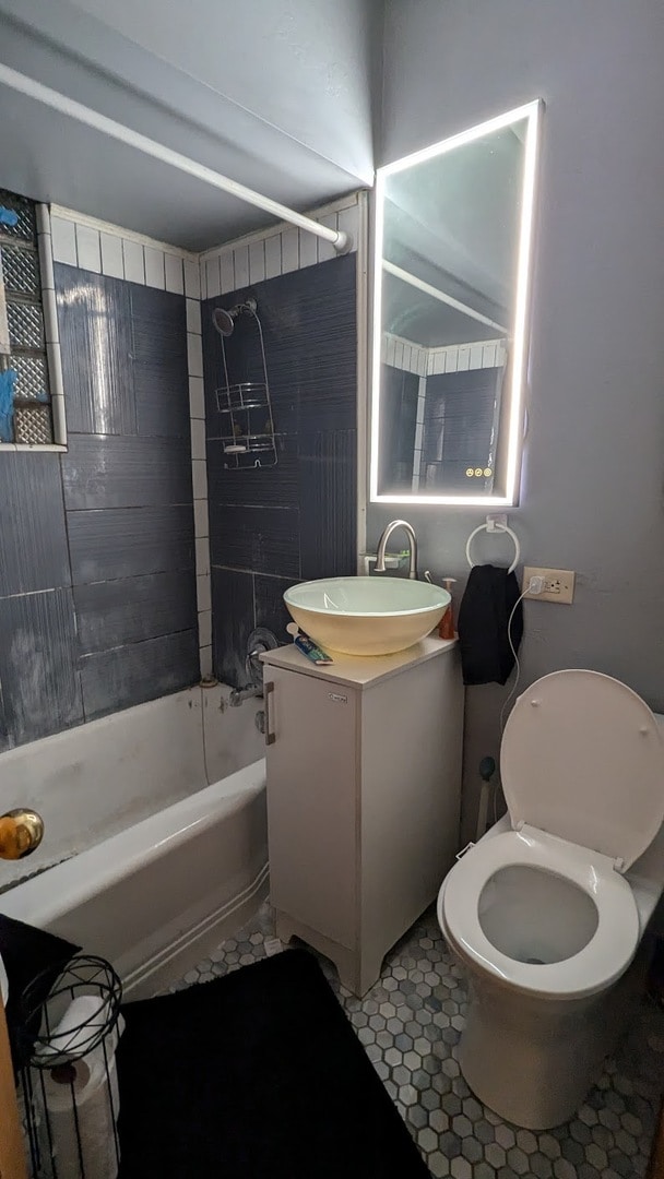 full bathroom featuring tile patterned flooring, vanity, tiled shower / bath combo, and toilet