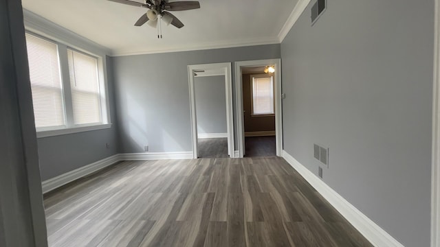 unfurnished bedroom featuring multiple windows, crown molding, dark hardwood / wood-style floors, and ceiling fan