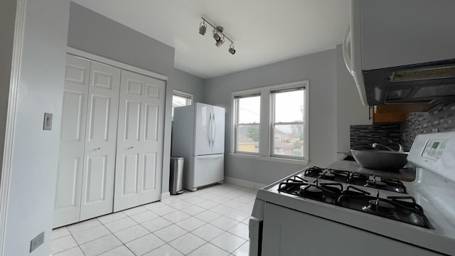 kitchen featuring track lighting, light tile patterned floors, backsplash, and white appliances