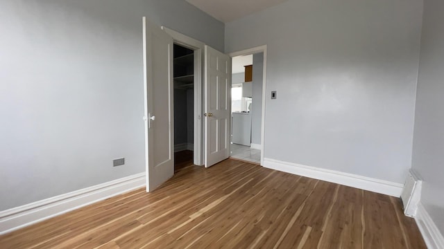 unfurnished bedroom featuring hardwood / wood-style flooring and washer / dryer