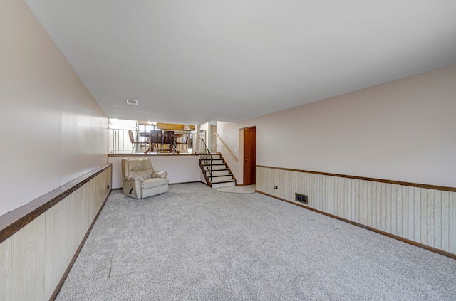 unfurnished room with wooden walls and light colored carpet