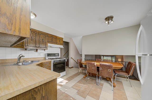 kitchen with decorative backsplash, light tile patterned floors, white appliances, and sink