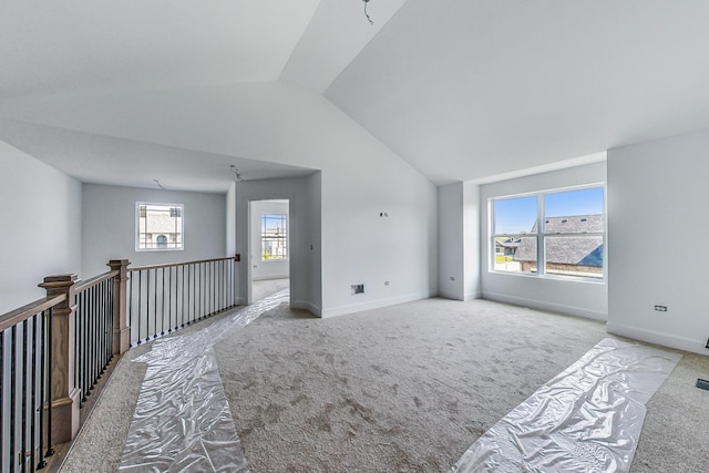 spare room with light colored carpet, plenty of natural light, and lofted ceiling