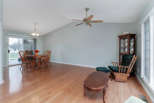 dining room featuring ceiling fan with notable chandelier, light hardwood / wood-style floors, and lofted ceiling