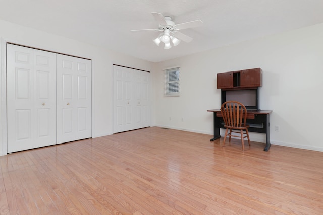 bedroom featuring light wood-type flooring, two closets, and ceiling fan