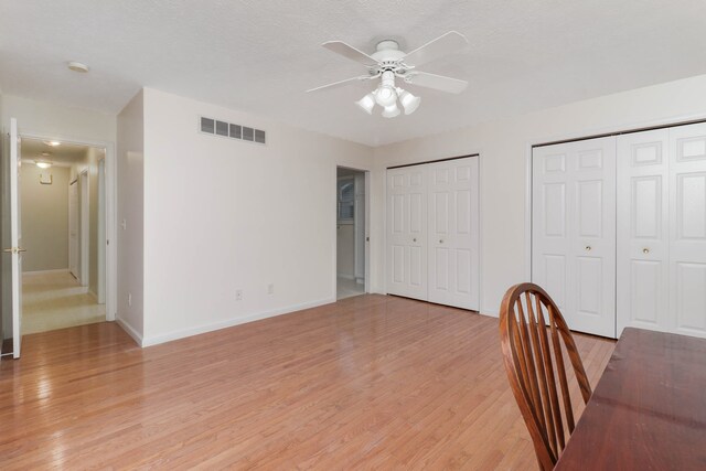 unfurnished office featuring ceiling fan, light hardwood / wood-style floors, and a textured ceiling