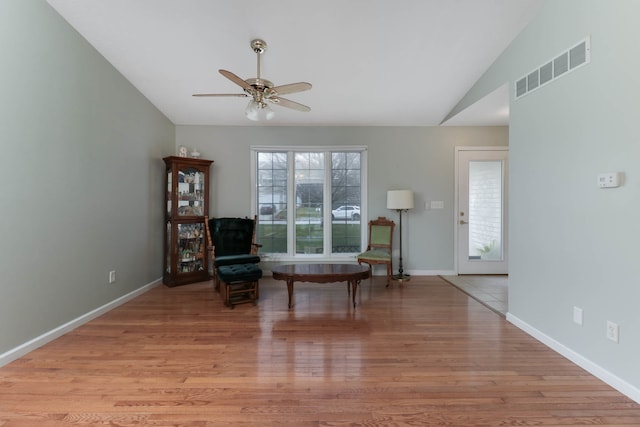 living area with ceiling fan, vaulted ceiling, and light wood-type flooring