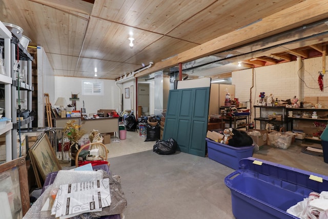 basement featuring wood ceiling and brick wall