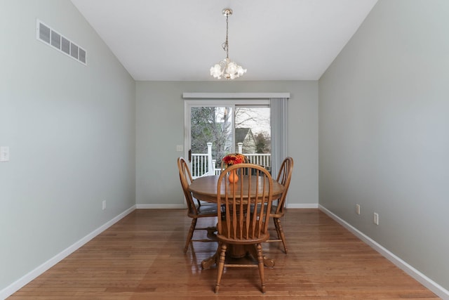 dining room featuring hardwood / wood-style floors, lofted ceiling, and an inviting chandelier