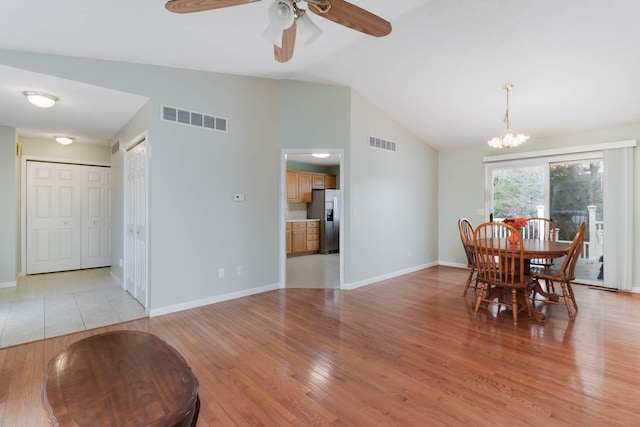 dining space featuring ceiling fan with notable chandelier, light hardwood / wood-style floors, and vaulted ceiling