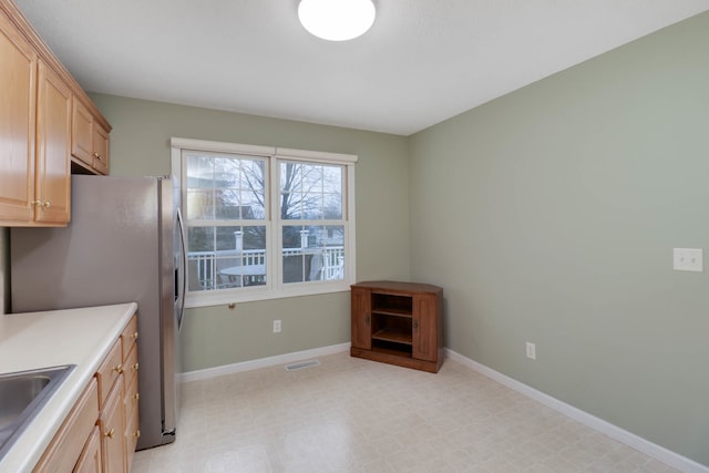 kitchen with light brown cabinets, stainless steel refrigerator, and sink