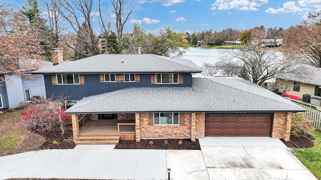 front of property with a garage, covered porch, and a water view