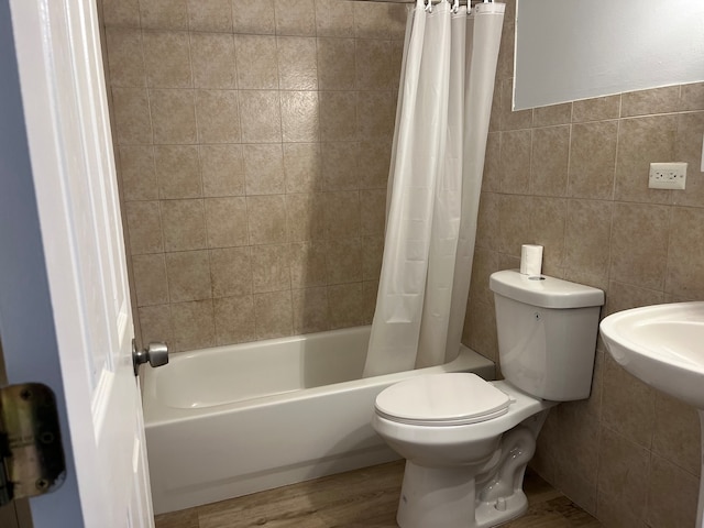 bathroom featuring hardwood / wood-style flooring, shower / bath combination with curtain, toilet, and tile walls