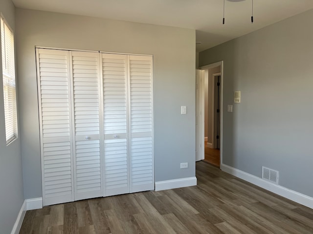 unfurnished bedroom with hardwood / wood-style floors and multiple windows