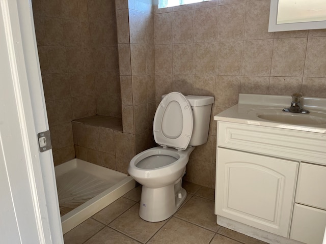 bathroom featuring walk in shower, tile patterned flooring, toilet, vanity, and tile walls