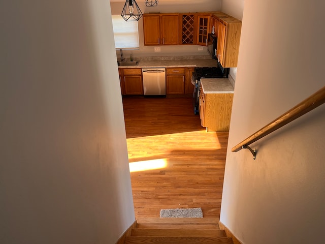 kitchen featuring black appliances, light hardwood / wood-style flooring, pendant lighting, and sink