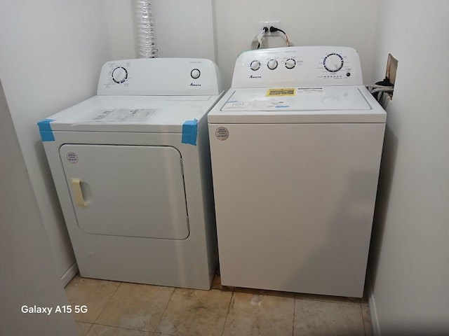 clothes washing area with washer and dryer and light tile patterned floors