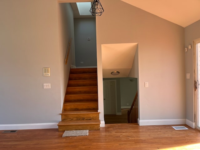 stairs with vaulted ceiling and hardwood / wood-style flooring