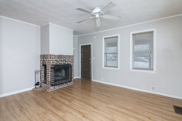 unfurnished living room featuring crown molding, light hardwood / wood-style flooring, ceiling fan, and a brick fireplace