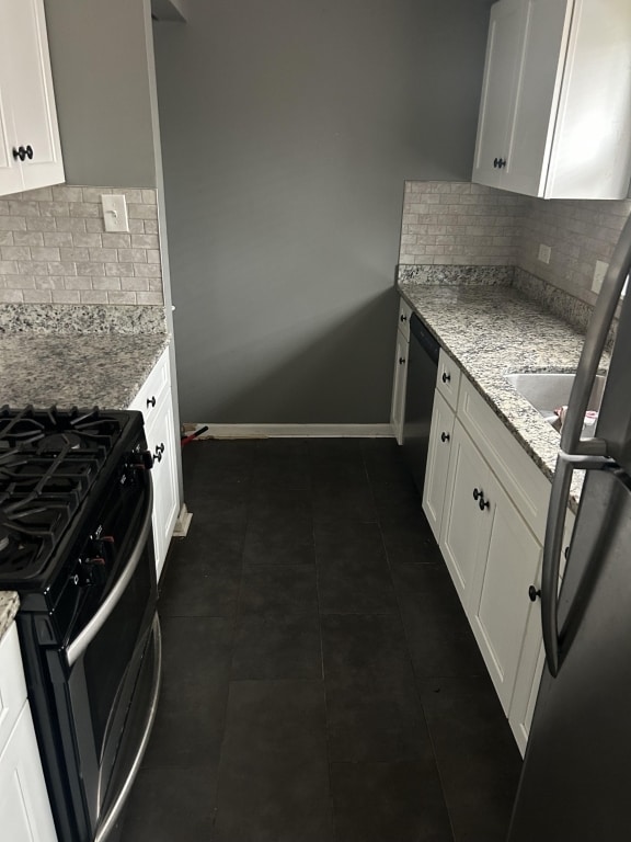 kitchen featuring light stone countertops, stainless steel appliances, and white cabinetry