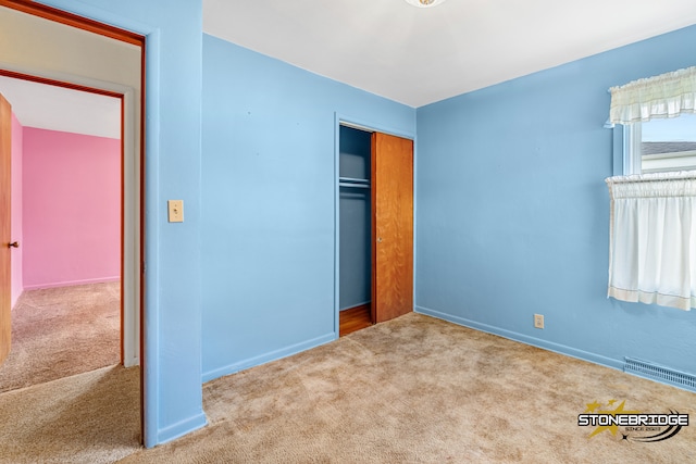 unfurnished bedroom featuring light colored carpet and a closet