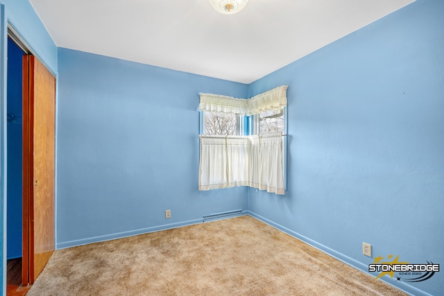 spare room featuring carpet floors and a baseboard heating unit